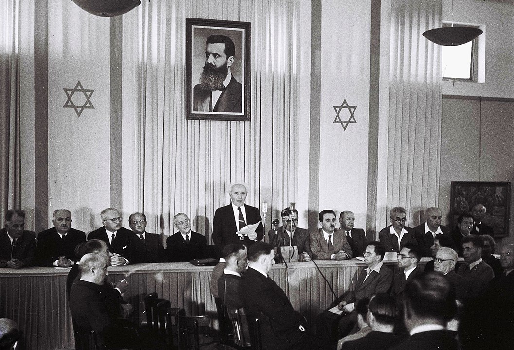 TEL AVIV, ISRAEL - MAY 14: In this handout from the GPO, David Ben Gurion, who was to become Israel's first Prime Minister, reads the Declaration of Independence May 14, 1948 at the museum in Tel Aviv, during the ceremony founding the State of Israel. (Photo by Zoltan Kluger/GPO via Getty Images) *** Local Caption *** David Ben Gurion. Public Domain File:Declaration of State of Israel 1948.jpg Created: 14 May 1948 Public Domain File:Declaration of State of Israel 1948.jpg Created: 14 May 1948. Wikipedia. Public Domain